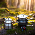 Compact 1-2 person aluminum cookware kit with kettle and nested pots on mossy log