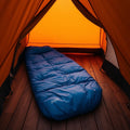 Blue 4-season mummy sleeping bag inside tent at dawn
