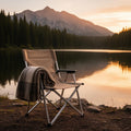 Aluminum folding camp chair beside an alpine lake at sunset