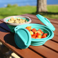 Collapsible silicone food bowls with lids on wooden picnic table