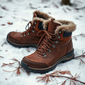 Brown leather waterproof winter hiking boots with fur-lined cuffs on snow